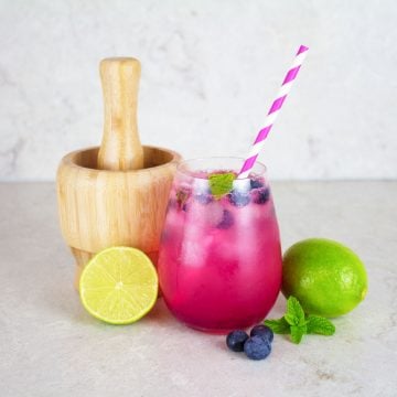 blueberry mocktail with lime and mint with wooden mortar and pestle