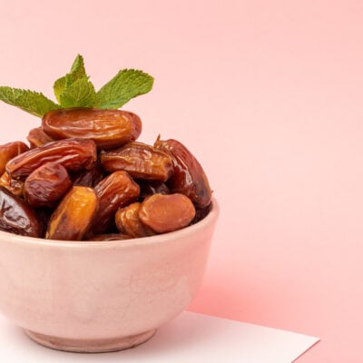 a pink bowl with whole dates inside garnished with mint