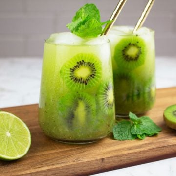 mocktail recipes kiwi in 2 glasses with gold straws and slices of lime and kiwi nearby