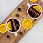 non alcoholic mulled wine flat lay looking down on 2 white mugs with orange slices, cinnamon sticks and mulled wine inside