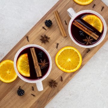 non alcoholic mulled wine flat lay looking down on 2 white mugs with orange slices, cinnamon sticks and mulled wine inside