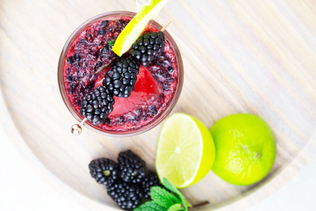 blackberry mocktail recipe birdseye view garnished with a cocktail pick with 3 blackberries and a lime wheel