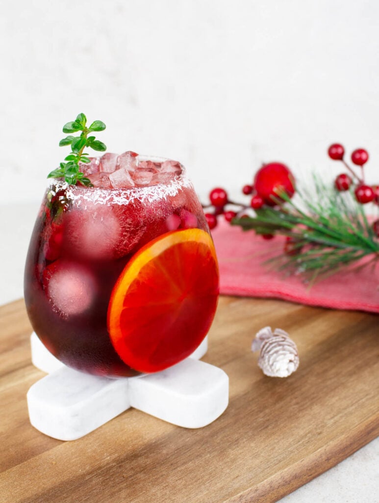 Christmas mocktail in a round glass with a coconut rim and sliced orange inside