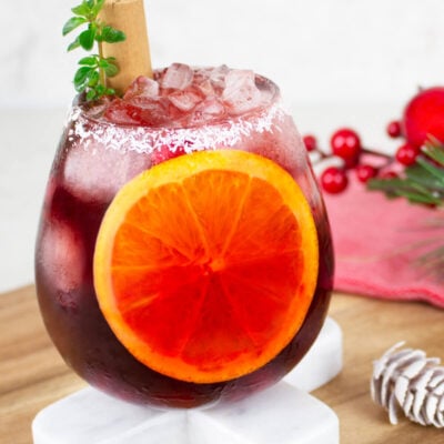 Christmas mocktail in a round glass with a coconut rim and sliced orange inside