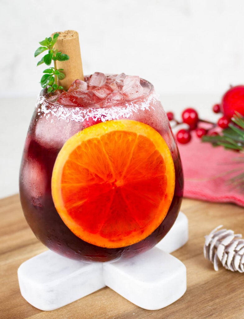 Christmas mocktail in a round glass with a coconut rim and sliced orange inside