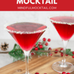 2 red Christmas mocktails in martini glasses with a lime and sugar rim