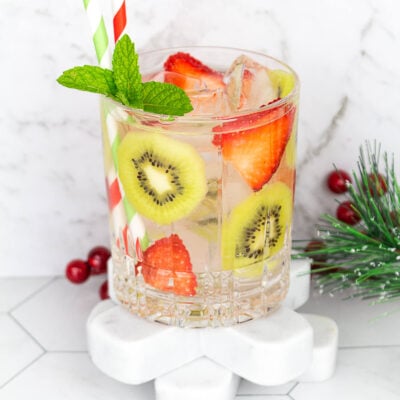 kiwi strawberry drink with ice and sparkling water with 2 red and green straws