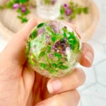 round ice block with frozen flowers in a purple and green colour.