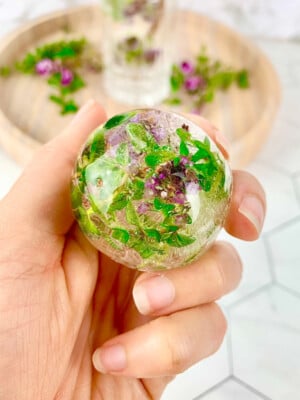 round ice block with frozen flowers in a purple and green colour.