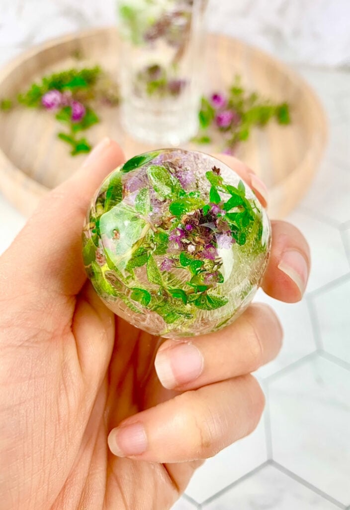 round ice block with frozen flowers in a purple and green colour.
