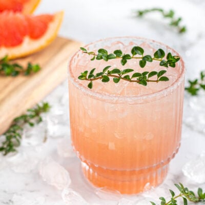 pink grapefruit mocktail in a short glass garnished with thyme