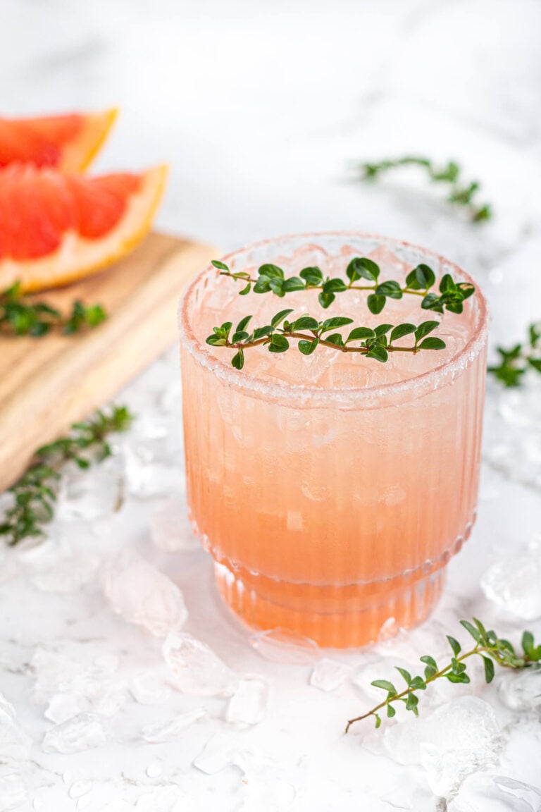 pink grapefruit mocktail in a short glass garnished with thyme