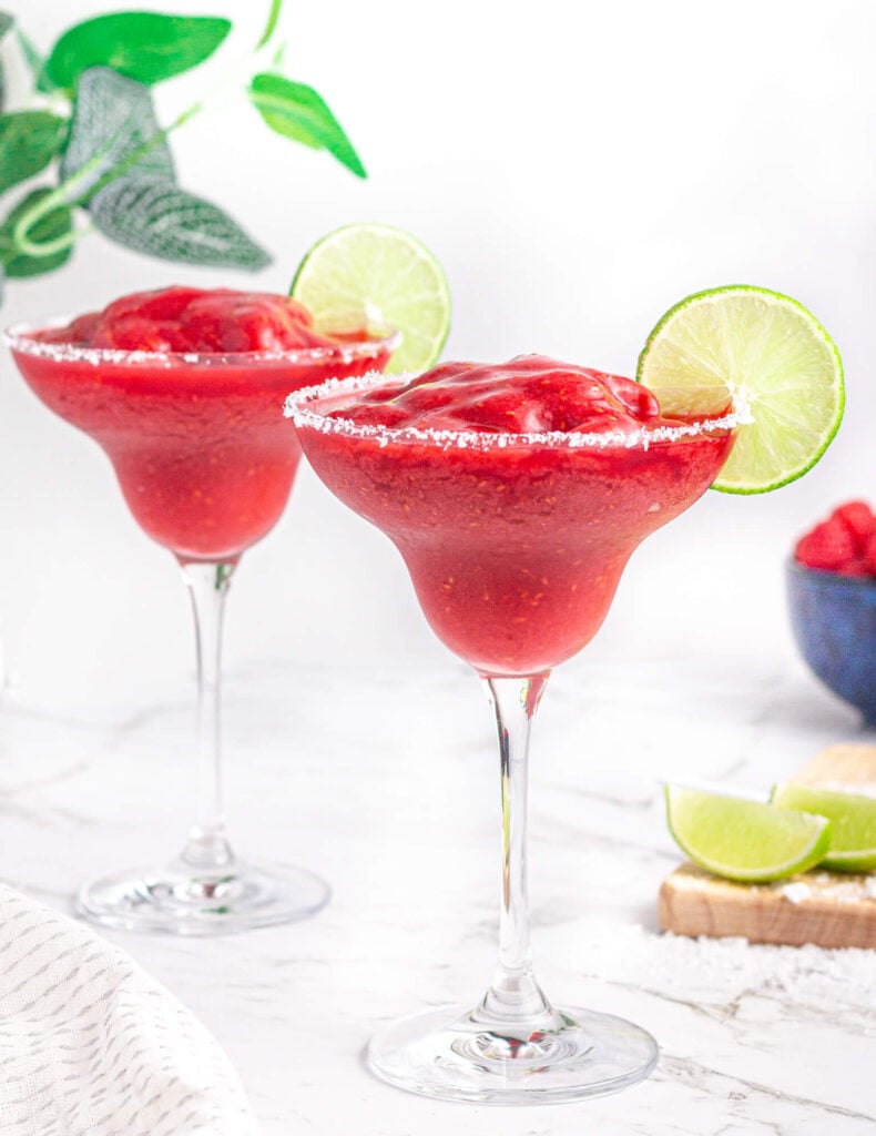 2 virgin raspberry margaritas with salt rims and lime wheel