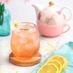 peppermint tea mocktail recipe in a pink glass with a teapot and lemon slices