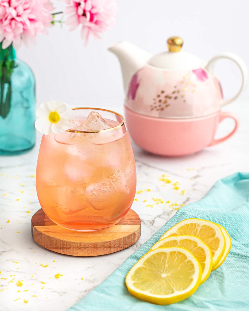 peppermint tea mocktail recipe in a pink glass with a teapot and lemon slices