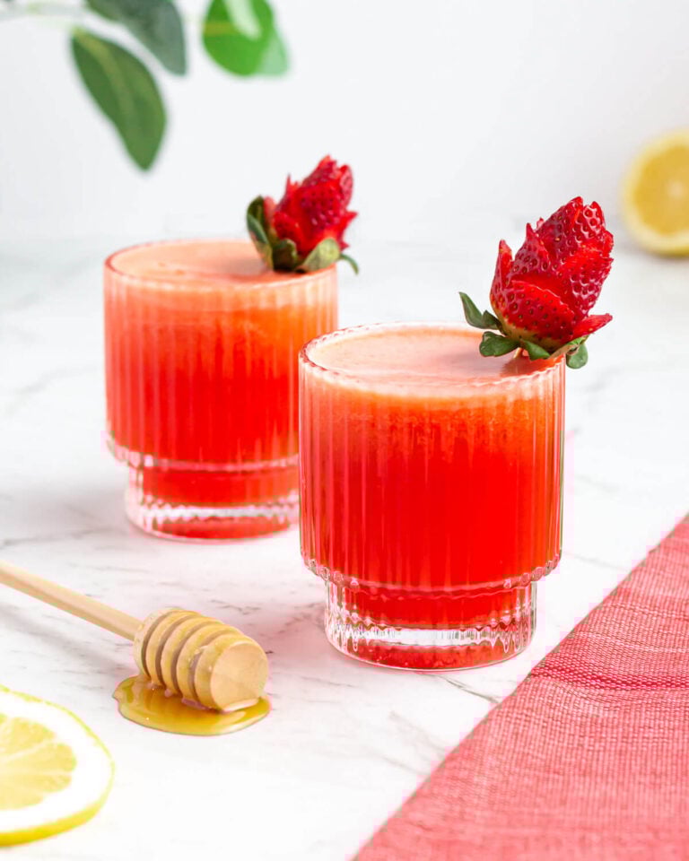 two glasses of strawberry lemonade garnished with roses made from strawberries