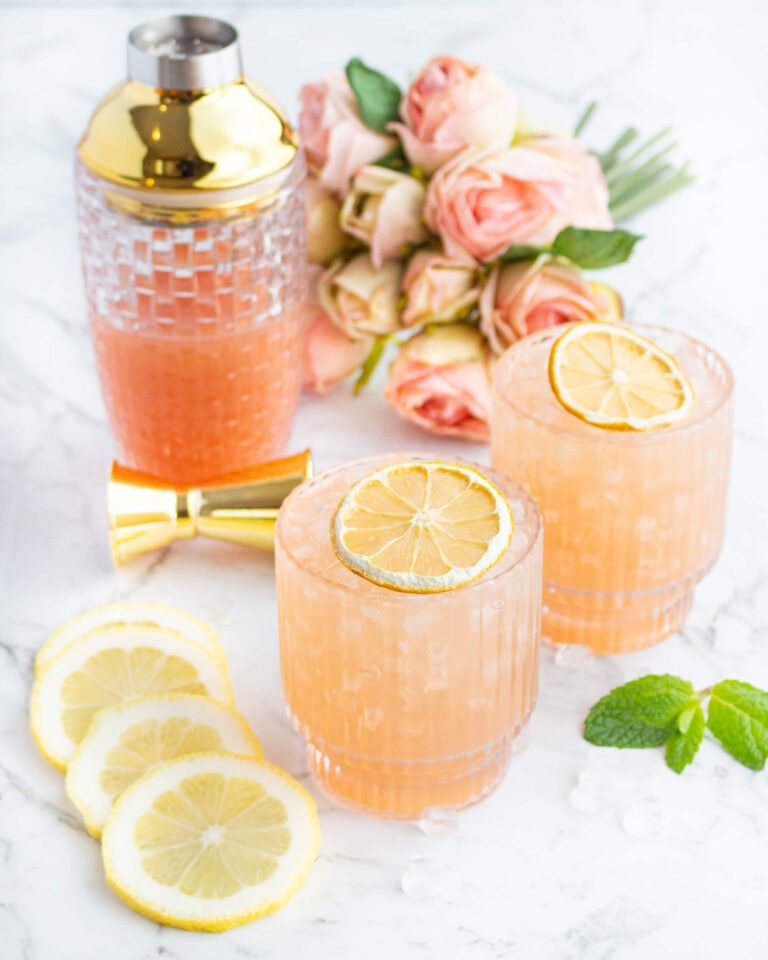 pink guava virgin cocktails garnished with dehydrated lemon with a cocktail shaker and pink flowers