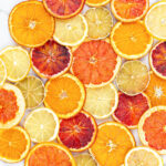 dried orange, blood orange, lime, grapefruit and lemon slices scattered on a grey background