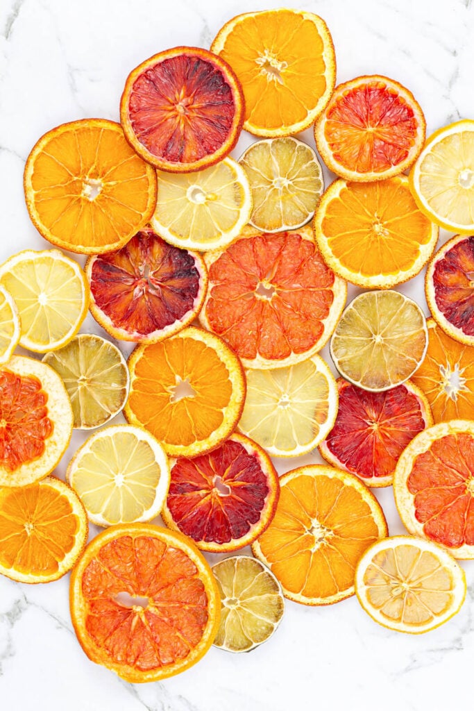 dried orange, blood orange, lime, grapefruit and lemon slices scattered on a grey background