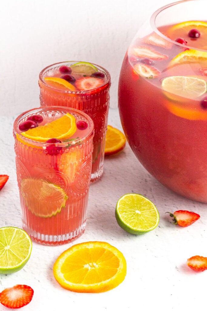 tall glasses of pink non-alcholic punch garnished with lime strawberry and orange