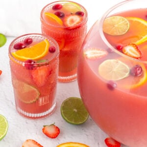 tall glasses of pink non-alcholic punch garnished with lime strawberry and orange