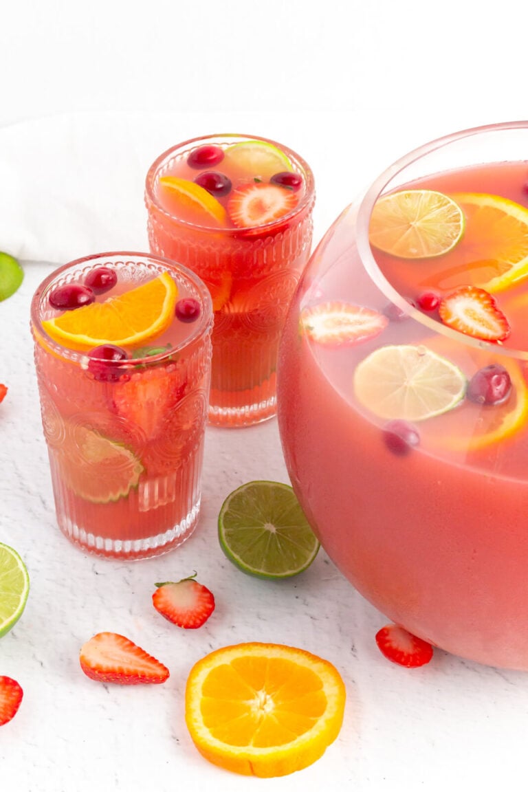 tall glasses of pink non-alcholic punch garnished with lime strawberry and orange