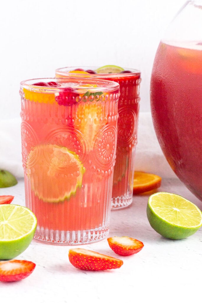 tall glasses of pink non-alcholic punch garnished with lime strawberry and orange