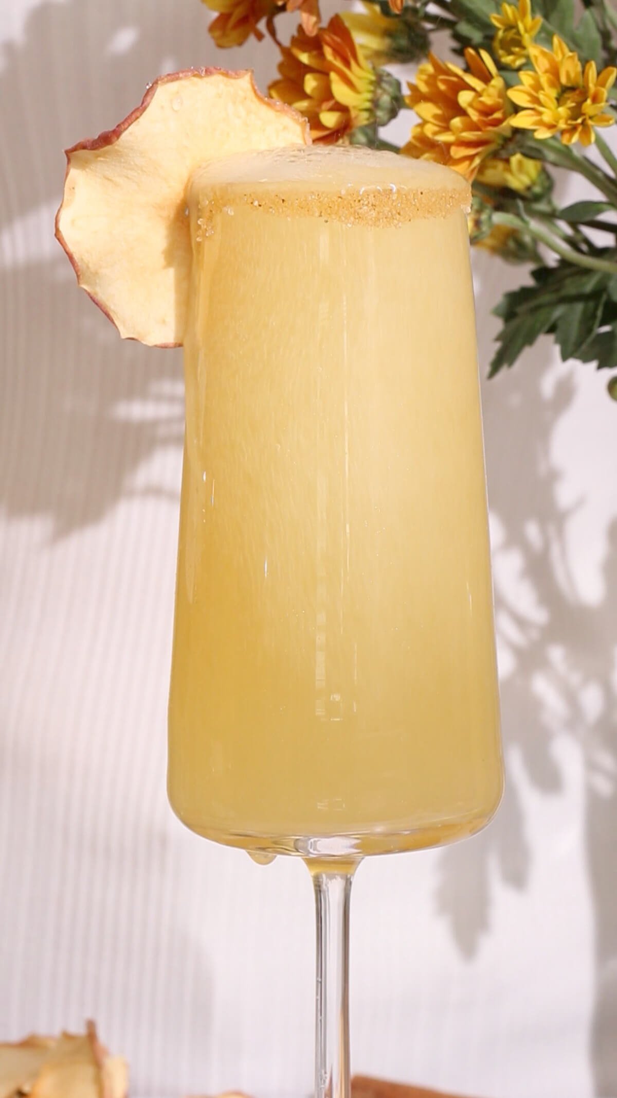 close up of a yellow mocktail in a champagne flute made with apple cider and non-alcoholic wine.