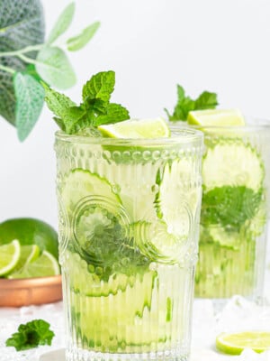 large tall glass with non-alcoholic mojito inside garnished with mint and lime.