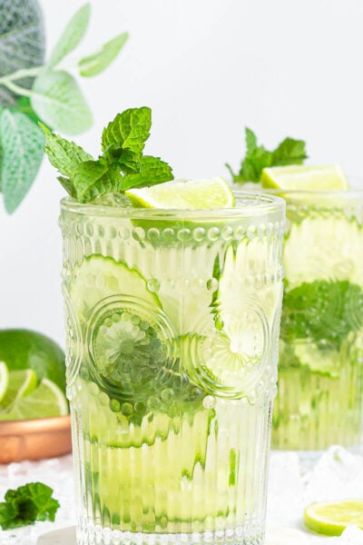 large tall glass with non-alcoholic mojito inside garnished with mint and lime.