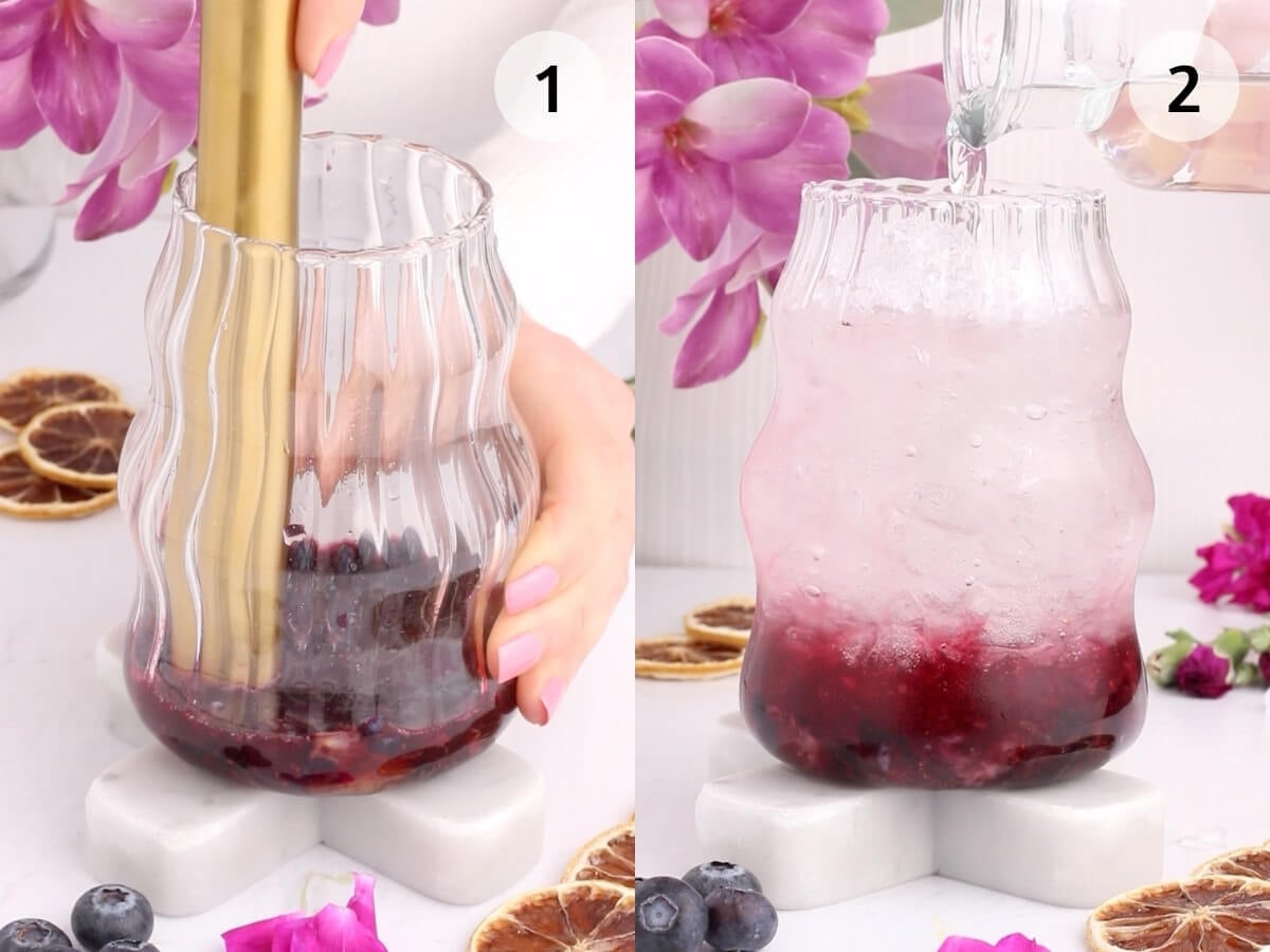 Side-by-side images show a hand muddling blueberries in a wavy glass (left) and pouring a clear liquid over ice and muddled berries in the same glass (right), with purple flowers and dried citrus in the background.